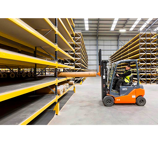 Forklift placing tube on warehouse shelving