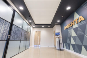 Modern office hallway with glass-walled rooms on the left and a geometric mural reading 'VIVANTA' on the right wall.