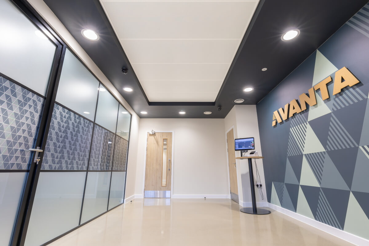 Modern office hallway with glass-walled rooms on the left and a geometric mural reading 'VIVANTA' on the right wall.
