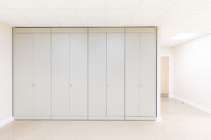 Row of tall grey storage cabinets lining a bright hallway.