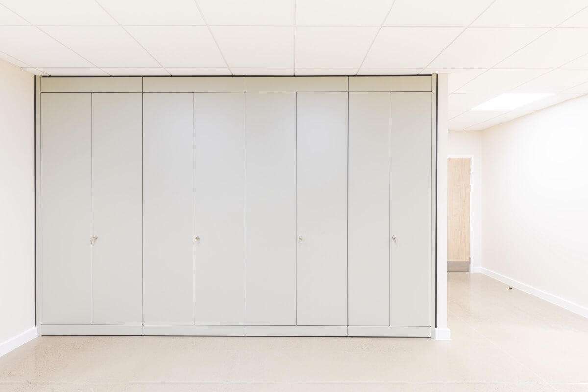 Row of tall grey storage cabinets lining a bright hallway.