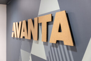 Cork letters spelling 'AVANTA' mounted on a geometric gray wall sign.