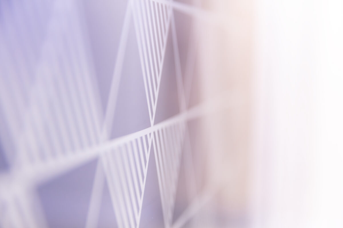 Abstract close-up of white diagonal lattice forming diamond shapes against a soft purple-to-peach gradient background.